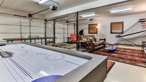 A room with a pool table, a sofa, and a projector mounted on the ceiling.