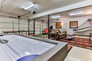 A room with a pool table, a sofa, and a projector mounted on the ceiling.