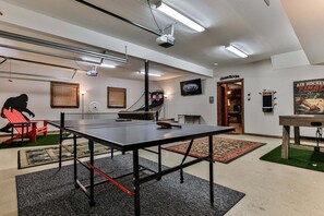 A ping pong table in a room with a projector, a TV, and a door labeled 'CAMEROOM'. - Fox Run Ridge | Ellijay, GA (Ellijay)