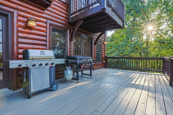 A wooden deck with a barbecue grill and a gas tank.