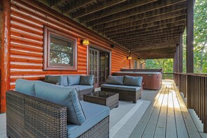 A covered porch with wicker furniture and a hot tub.
