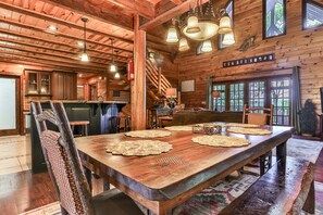 A rustic wooden interior with a large dining table, wooden chairs, and a bar area. - Fox Run Ridge | Ellijay, GA (Ellijay)