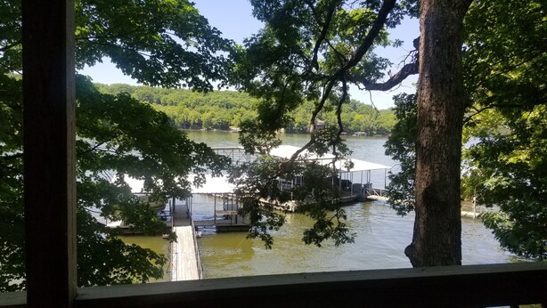 A view of a lake with a dock and boats, surrounded by trees. -  Cozy Lake Front Cottage w/dock, perfect family retreat! (Camdenton)