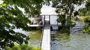 A wooden bridge leading to a dock over a calm body of water, surrounded by greenery. -  Cozy Lake Front Cottage w/dock, perfect family retreat! (Camdenton)