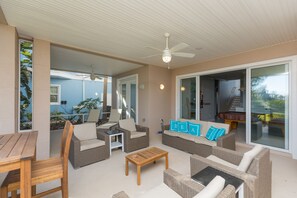 An outdoor living area with wicker furniture, a wooden table, and a ceiling fan.