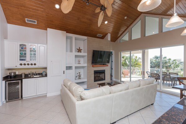 A modern kitchen with white cabinetry, a built-in oven, and a dining area with a white sofa and table.