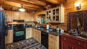 A wooden cabin interior with a kitchen featuring cabinets, a stove, a sink, and a refrigerator. - Water's Edge | Blue Ridge, GA (Blue Ridge)