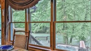 A room with a large window, a wooden table, and a chair. - Lofty Pines on the Cartecay | Ellijay, GA (Ellijay)