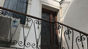 Un edificio blanco con un balcón que presenta barandillas de hierro forjado ornamentadas y una ventana con una puerta decorativa.