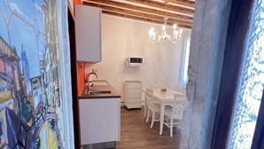 Una cocina moderna con armarios blancos, microondas y una zona de comedor con sillas y una mesa blancos.