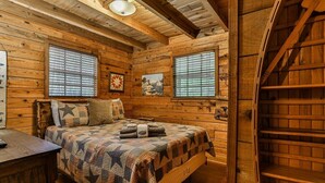 Une pièce dans une cabane en bois, comprenant un lit, un bureau et un escalier.