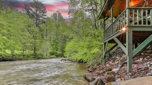 Une terrasse en bois surplombant une rivière, entourée d’une forêt dense.
