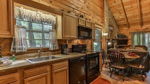 L’intérieur d’un chalet en bois comprend une cuisine, un coin repas et une cheminée.