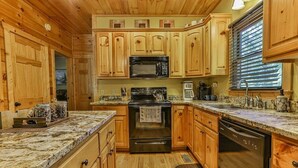 A kitchen with wooden cabinets, a microwave, stove, and dishwasher. - Whitetail Ridge | Ellijay, GA (Ellijay)