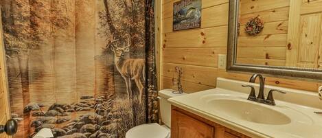 Baño con un mural de ciervo, un letrero de cabaña de madera, un lavabo y un espejo.