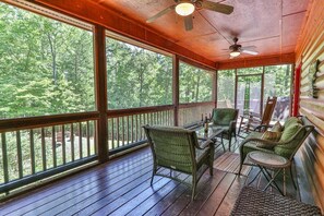 A covered porch with wooden flooring, wicker furniture, and a ceiling fan. - Whitetail Ridge | Ellijay, GA (Ellijay)