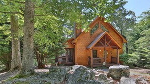A log cabin with a porch, surrounded by large rocks and trees. - Whitetail Ridge | Ellijay, GA (Ellijay)