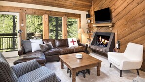 Ein gemütliches Wohnzimmer mit Kamin, Ledersofas und einem Fernseher.