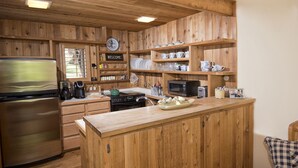 Eine Küche mit Holzausbau, einem Edelstahlkühlschrank, einer Mikrowelle und einer Holzinsel mit einer Schüssel Eier.