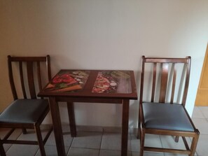 A dining table with a floral tablecloth and two wooden chairs with cushioned seats. - Zante Dolphin (Zakynthos)