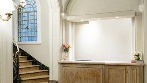 A grand staircase with marble steps and a wooden paneling wall. - Patios de Recoleta (Buenos Aires)