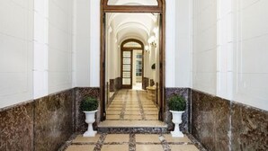 A hallway with a marble floor, white walls, and a wooden-framed door labeled "AQUA". - Patios de Recoleta (Buenos Aires)