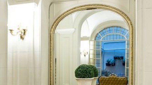 A grand hallway with a large mirror, a marble floor, and a green plant in a white vase. - Patios de Recoleta (Buenos Aires)