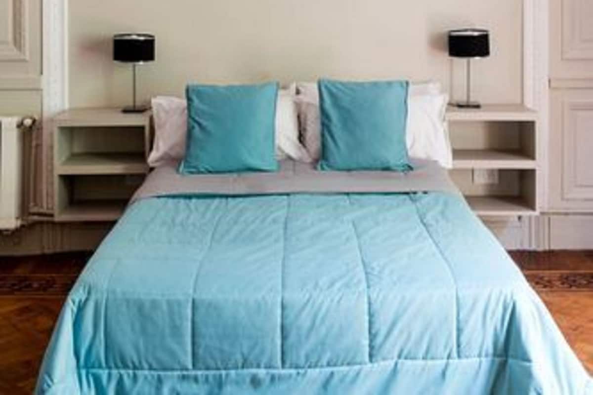 A bedroom with a large bed, two bedside tables, and a white arched headboard.