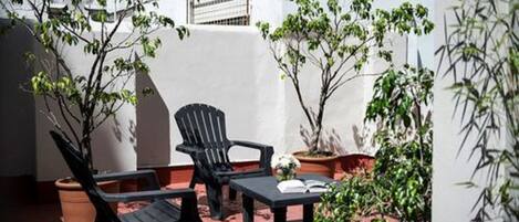 Un área de estar al aire libre con una mesa, dos sillas y plantas en macetas.