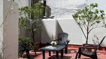 Un patio al aire libre con una mesa, sillas y plantas en macetas.