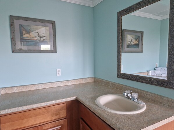 A bathroom with a sink, mirror, and two framed pictures on the wall.