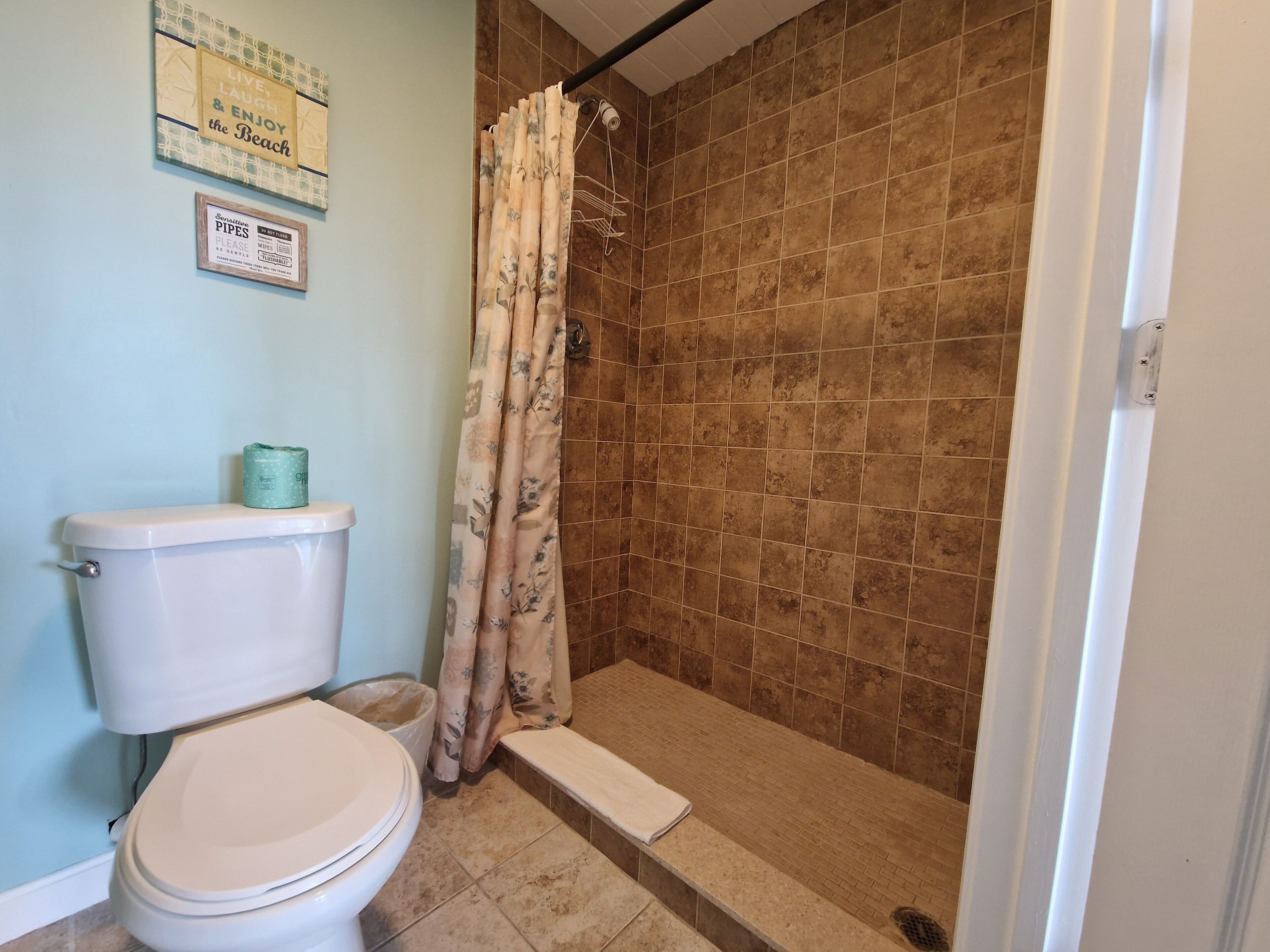 A bathroom with a toilet, shower, and tiled walls.