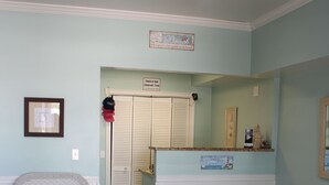 A room with a reception desk, a wicker chair, a door with a sign, and a framed picture on the wall.