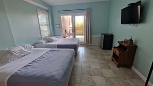 A hotel room with two beds, a ceiling fan, a TV, and a view of the outside.