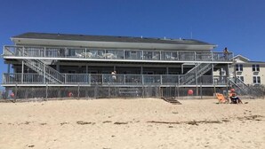 A multi-story building with balconies, a staircase, and a beach in the foreground.