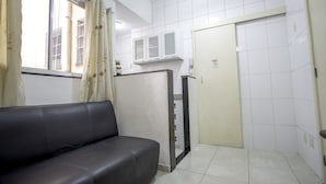 A room with a black leather sofa, a white tiled wall, a door with a sign, and a window with curtains. - LineRio Copacabana Residence 189 (Rio de Janeiro)