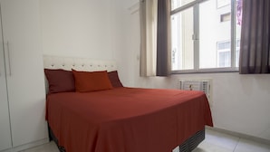 A bedroom with a bed, a window with curtains, and a radiator. - LineRio Copacabana Residence 189 (Rio de Janeiro)