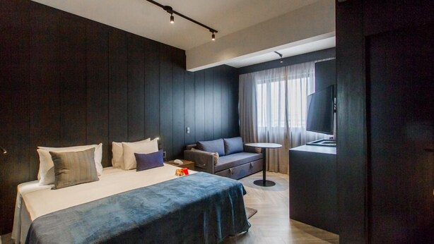 A modern hotel room with a large bed, a sofa, a TV, and a small table. - VN Bela Cintra (Sao Paulo)