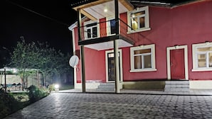 A two-story building with a balcony, a satellite dish, and a red door. - Kriyus (Gabala)