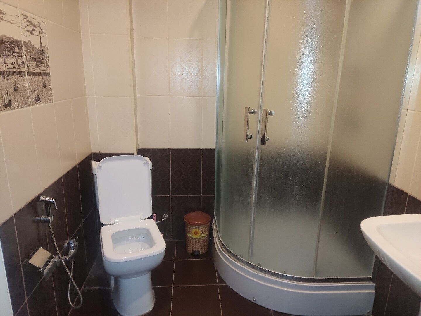 A bathroom with a toilet, shower, and sink.