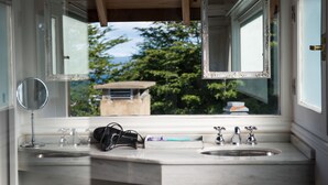 A bathroom with two sinks, a mirror, and a window with an open frame.