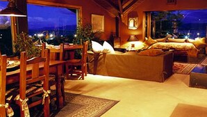 A cozy room with a large window, a sofa, a dining table, and a lamp.