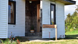 A white building with a wooden door and a sign that reads "Reception". - Vista Tranquila Chiloe (Chonchi)