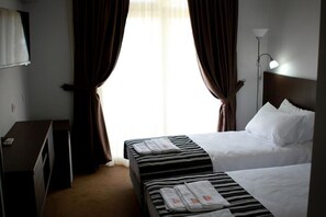 Habitación de hotel con dos camas, un escritorio y una lámpara.