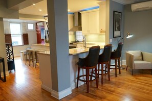 A modern kitchen with a central island, bar stools, and a dining area with a sofa. - 3-Level Bucktown Home - Amazing Outdoors & Parking (Chicago)