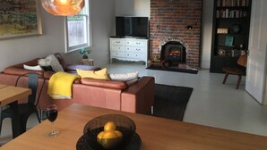 A living room with a brick fireplace, a television, a bookshelf, and a dining area with a table and chairs. - Signature on Gunn (Devonport)