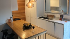 A modern kitchen with a wooden countertop, two pendant lights, a wine glass, and a cookbook on the counter. - Signature on Gunn (Devonport)