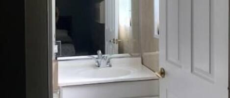 A bathroom with a white sink, mirror, and cabinets.