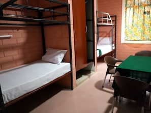 A dormitory room with bunk beds, a table, and chairs. - Kilimanjaro Eco Hostel (Moshi)