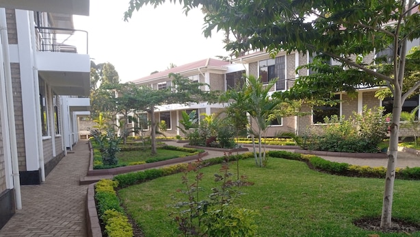 A courtyard with a brick pathway, neatly trimmed grass, and small trees. - Kilimanjaro Eco Hostel (Moshi)